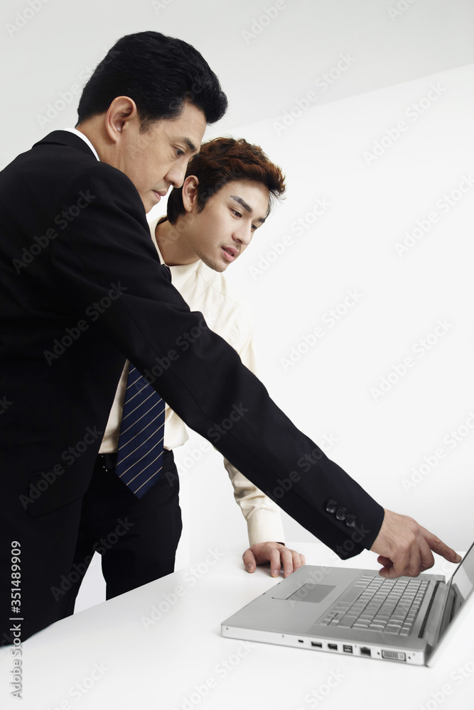 Businessmen referring to laptop for work discussion Businessmen referring to laptop for work discussion