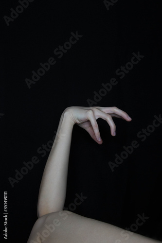 An abstract figure consisting of female arms and legs, resembling a tree branch. Art. The art of the naked body. Bending his arms. Hands and feet on a black background.