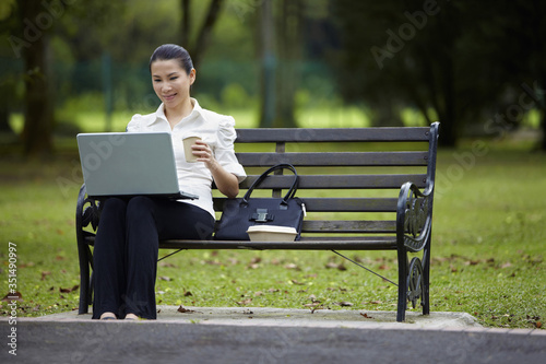 Mid adult businesswoman working in the park during coffee break