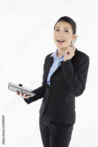 Mid adult businesswoman writing notes in organizer © ImageHit