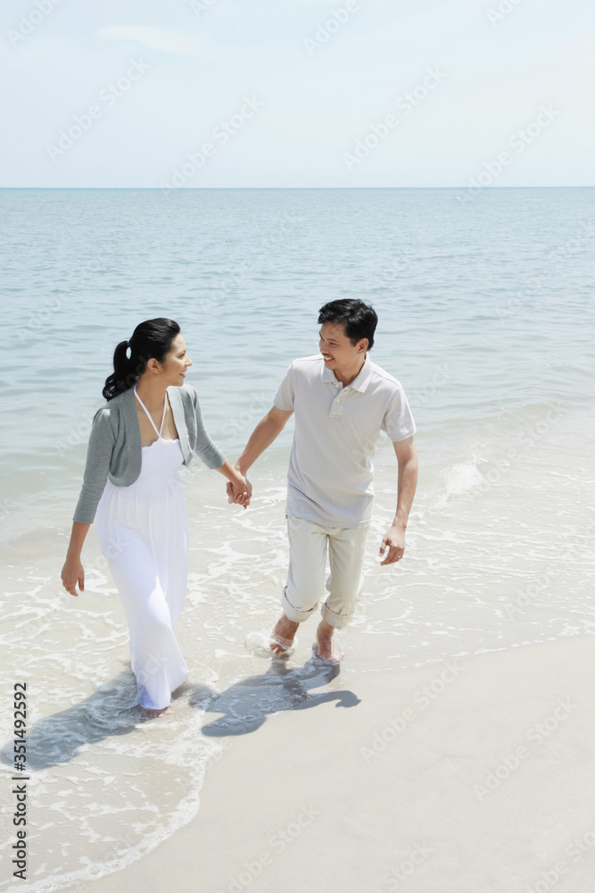 Man and woman holding hands while walking on the beach Man and woman holding hands while walking on the beach