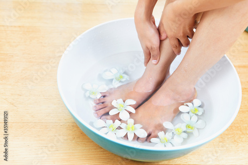 Feet in a bowl of water with flowers