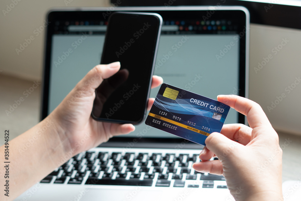 Business woman hand hold credit card to shopping internet online bill on computer, Debit saving purchase buy on table background. Shopaholic people retail pay sale money, bank terminal account concept