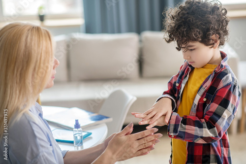 Blonde female and curly boy rubbing hands with antiseptic