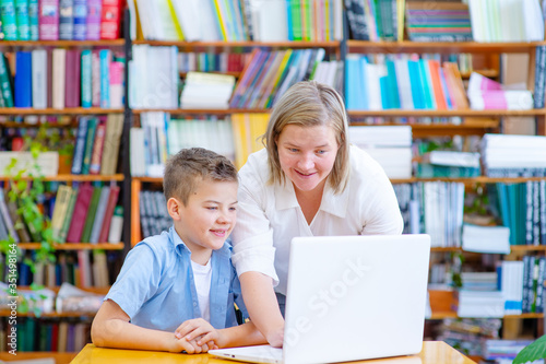 The teacher helps the student to work on a laptop in the library. Learning Assistance Concept