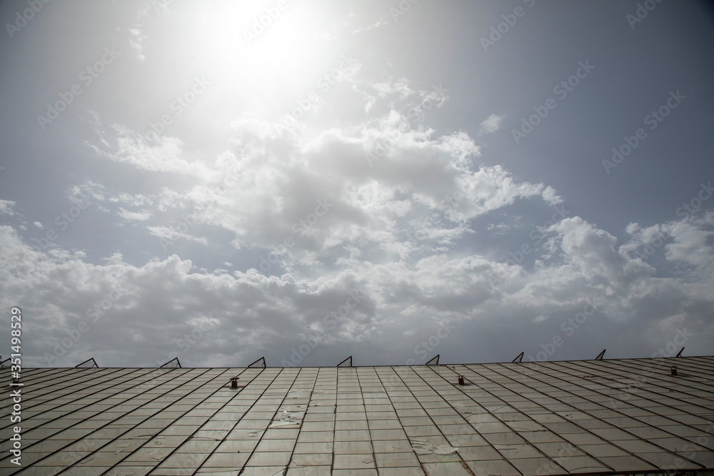 a glass roof and cloudy sky