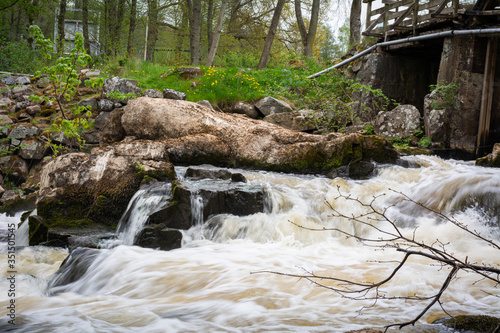 Turbulent river rapids under an old wooden bridge in Scania, southern Sweden. photo