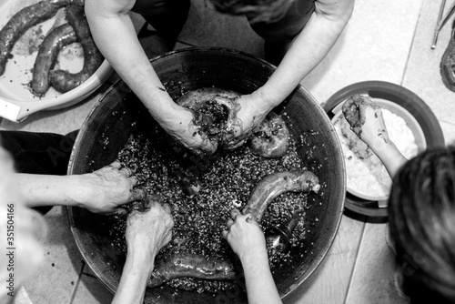 Manos de mujer rellenando tripas durante la elaboración casera de morcillas de arroz de Burgos según el método tradicional, blanco y negro. Tomada el 20 de febrero de 2020 en Burgos, Castilla y León.
