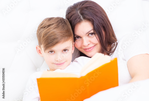 Mom and son read a book before going to bed. Looking at the camera © Ermolaeva Olga