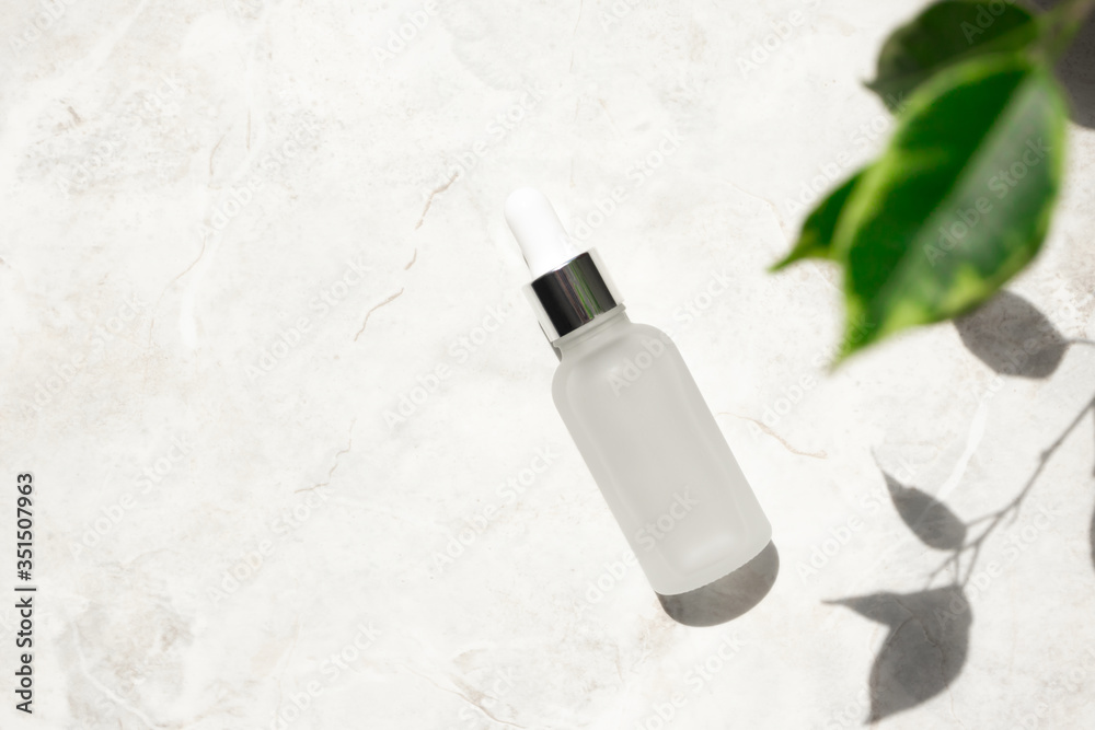 Serum with vitamin E and collagen in frost glass bottle on marble background. Concept of natural cosmetic with copy space at left Serum with vitamin E and collagen in frost glass bottle on marble background. Concept of natural cosmetic with copy space at left