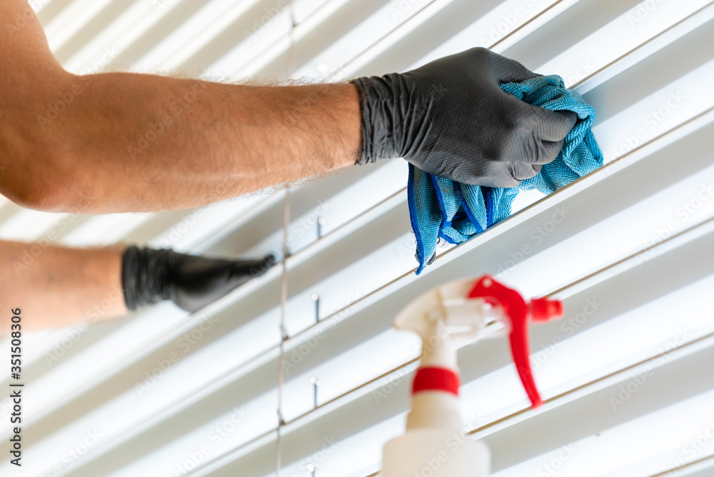 caucasian man cleaning professionally cleaning window blinds with a micro fiber cloth and cleaning detergent