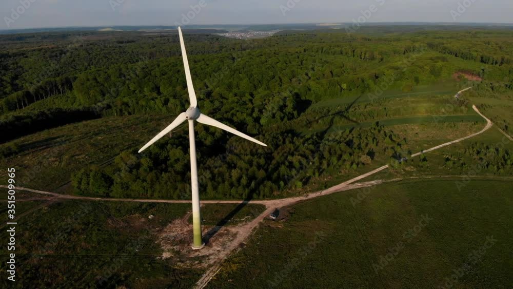 AERIAL: Close up shot of wind Turbine, Mill rotating by the force of the Wind Generating Renewable Energy in a Green Ecologic way for the Planet over beautiful Green Agriculture field AERIAL: Close up shot of wind Turbine, Mill rotating by the force of the Wind Generating Renewable Energy in a Green Ecologic way for the Planet over beautiful Green Agriculture field