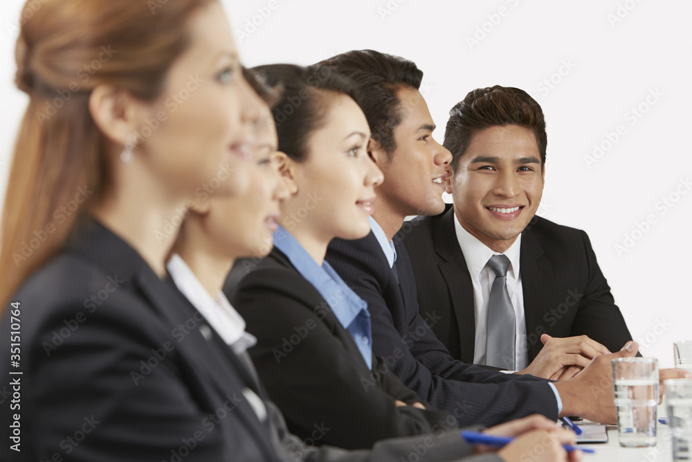 Side view shot of business people sitting together Side view shot of business people sitting together