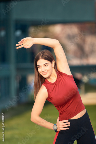Young sporty woman stretching and exercising in urban park.