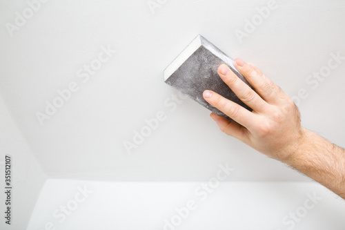 Принти на полотні Worker hand polishing white ceiling with sanding sponge. Closeup.