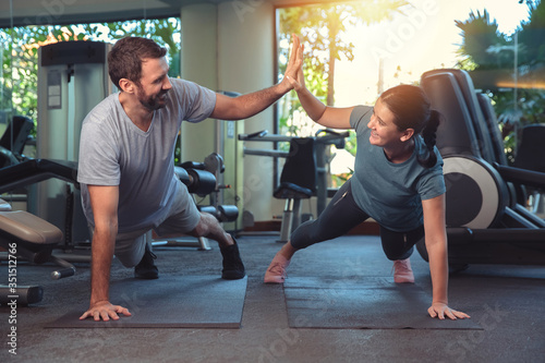 Couple exercise together in gym. Man and woman working out in fitness club doing plank exercise. Healthy lifestyle, training in gym.