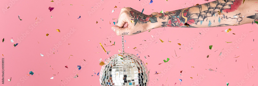 Φωτογραφία Tattooed hand holding a Christmas disco ball and confetti in the air