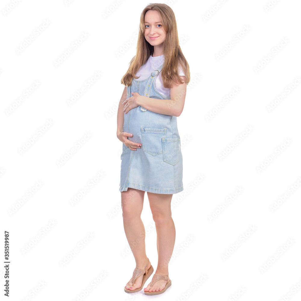 Pregnant woman in denim sundress standing looking smiling on white background isolation Pregnant woman in denim sundress standing looking smiling on white background isolation