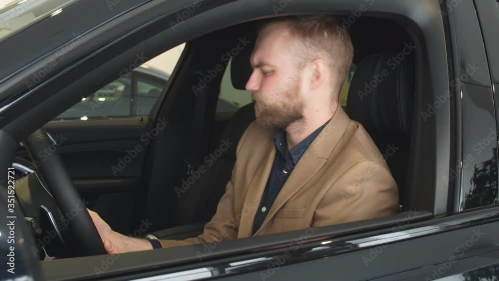 Perfect auto in dealership. Young handsome caucasian guy examining new car before making purchase. Perfect auto in dealership. Young handsome caucasian guy examining new car before making purchase.