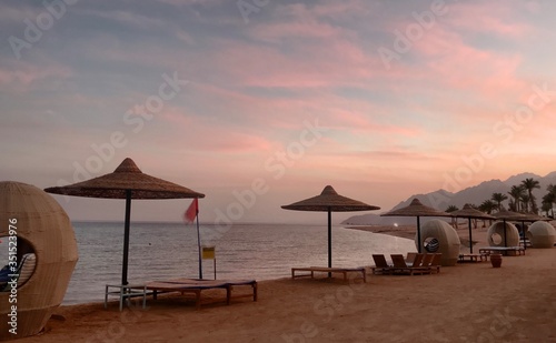 Fototapeta Naklejka Na Ścianę i Meble -  Beach furniture in front of a pink sunset by the ocean in South Sinai, Egypt