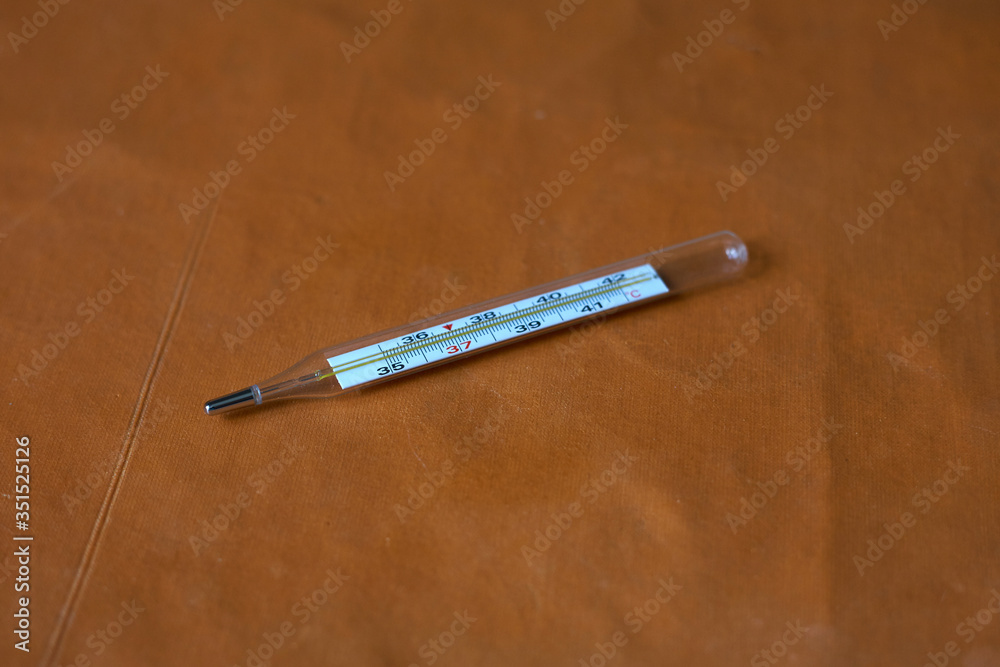 A medical thermometer lies on a couch. The couch is brown A medical thermometer lies on a couch. The couch is brown