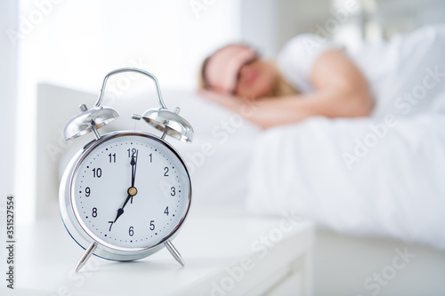 Profile photo of charming lady lying sleeping bed white sheets blanket clothes calm sure metal alarm clock will ring at sever o'clock morning work monday wear pajama room indoors