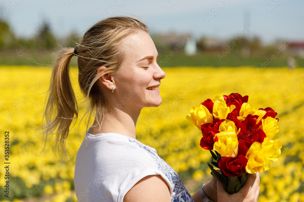 Naklejka premium The young woman with tulips in the tulip field