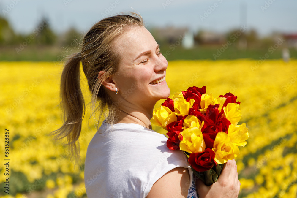 Naklejka premium The young woman with tulips in the tulip field