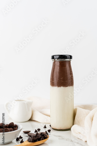 Chocolate milk in bottom glass on white wood background Fresh chocolate milk with copy space banner cover background.