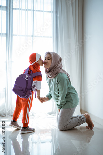muslim daughter shake hand and kiss mother before going to school in the morning