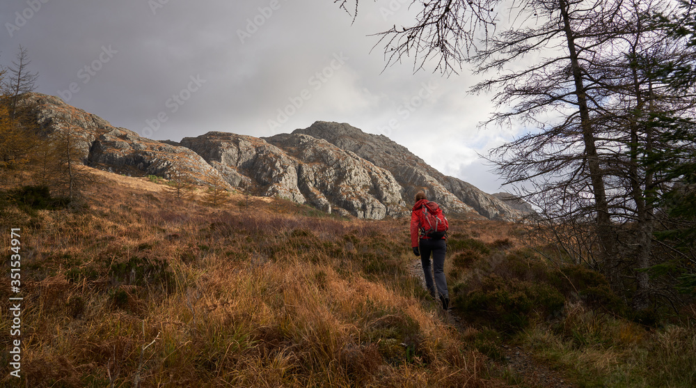 A hiker in a red jacket walking up from Inverianvie river towards Creag Mheall near Gruinard Bay in the Scottish Highlands, Scotland, UK.