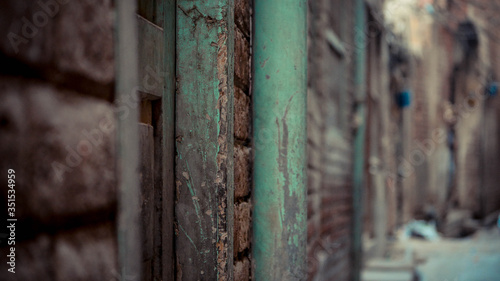 Green rusty pole mounted on the brick wall