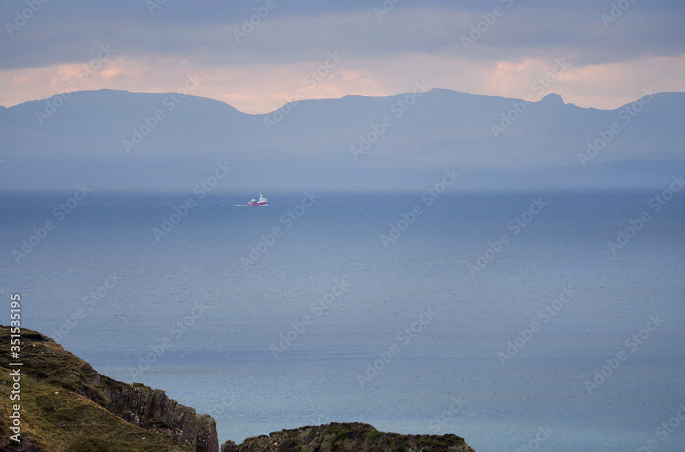 A fishing trawler out catching fish on Loch Gairloach as a rain shower comes in from the Torridon mountains in the Scottish A fishing trawler out catching fish on Loch Gairloach as a rain shower comes in from the Torridon mountains in the Scottish