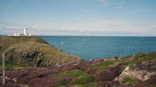 Yacht sailing past Strumble Head Lighthouse Fishguard Pembrokeshire Wales  photo