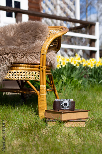 Old-fashioned camera and the old books in the grass.Sunny spring time day. Horizontal.
