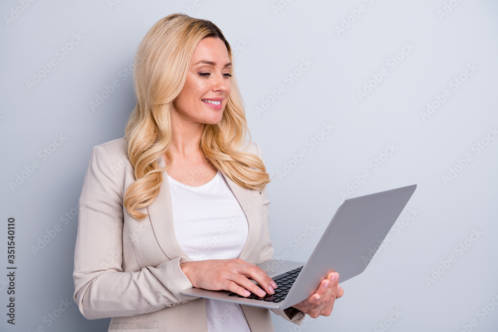 Photo of satisfied glad clever lady using netbook for working on the project isolated over grey background Photo of satisfied glad clever lady using netbook for working on the project isolated over grey background