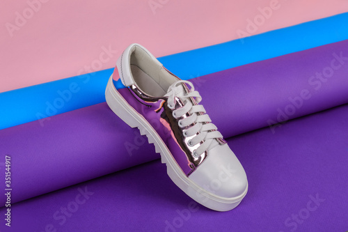 Stylish woman shoe on a colorful paper roll. Creative footwear design concept.