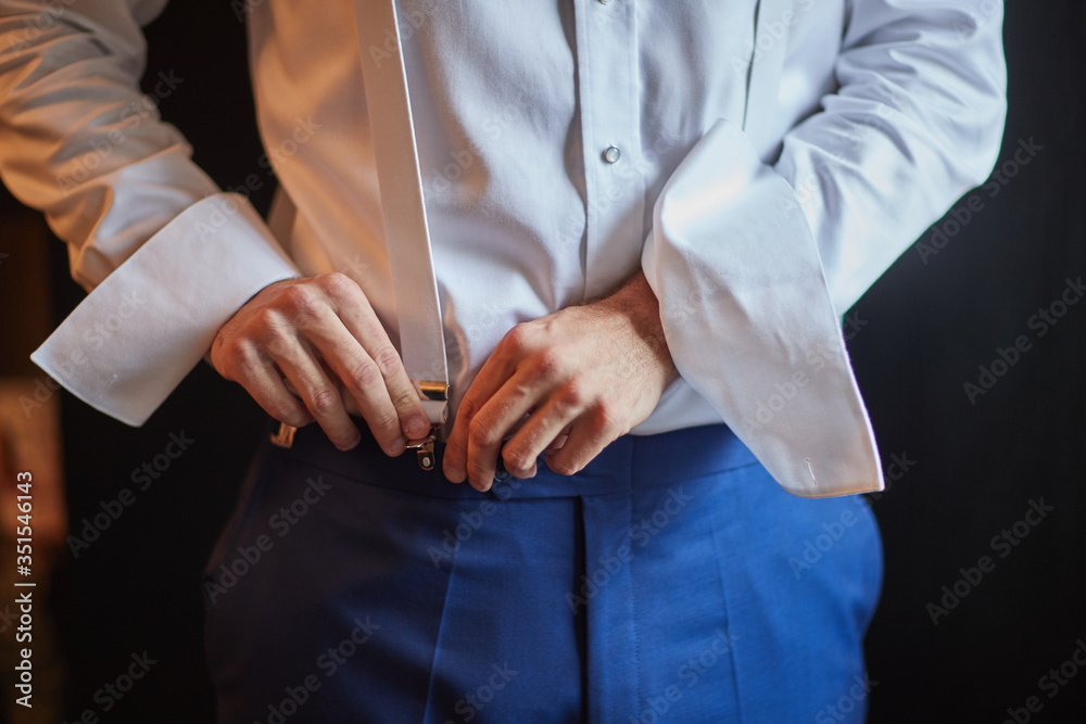 the groom puts on his wedding suit in preparation for the wedding ceremony