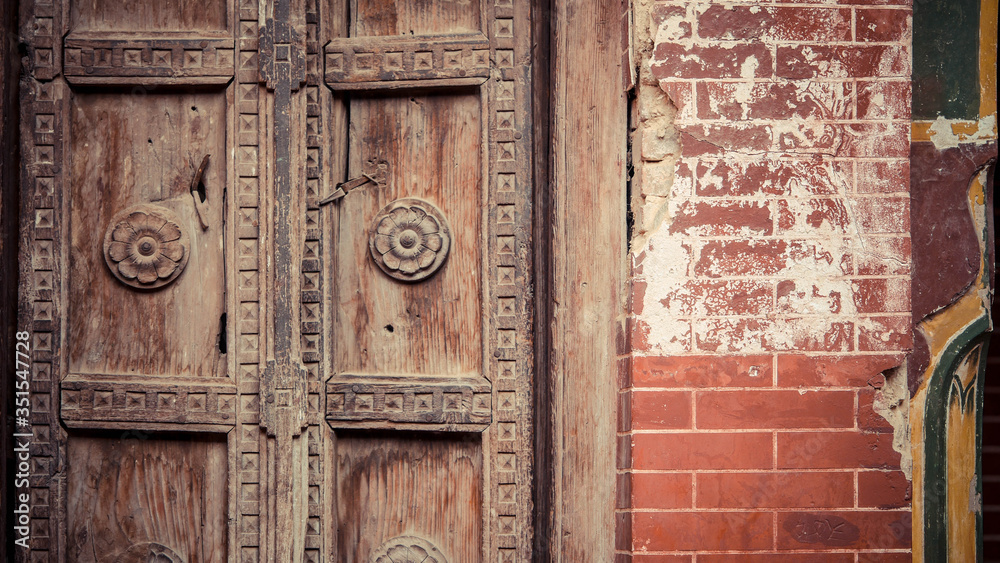 Wooden doors with carving next to brick walls