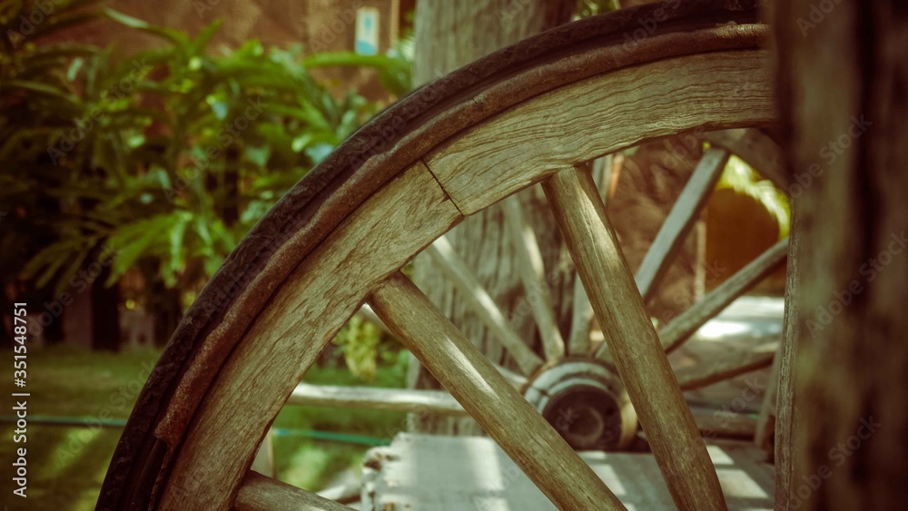 Wooden wheels of a cargo bed next to tree
