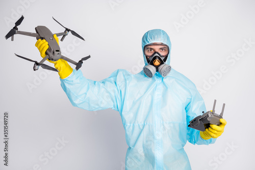 Portrait of man hold joystick airplane drone fly air sky monitor surface wear white suit hazmat yellow rubber latex gloves glasses goggles breathing mask isolated grey color background