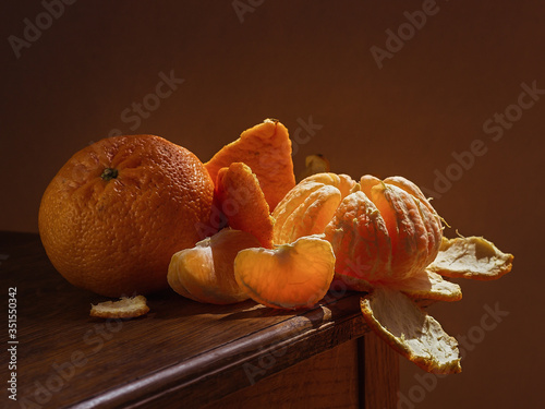 Juicy orange white tangerine or mandarin, on a wooden table, with a dark background, soft light. Imitation of a Dutch kitchen still life. Mono food.