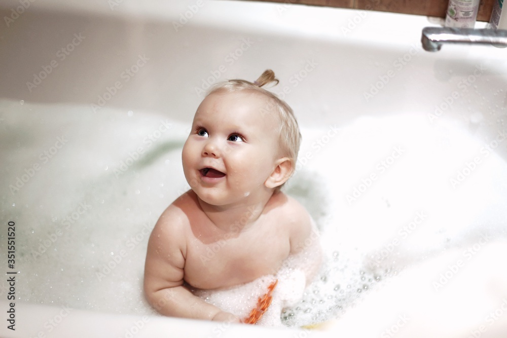 Portrait of a cute baby bathing in a bath with foam closeup
