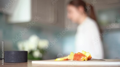 Cooking with the functions of a smart home. A young woman uses a voice assistant in her kitchen closeup