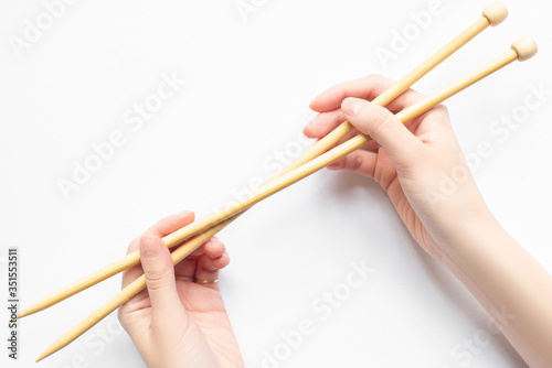 top view of female hands with knitting needles on white background