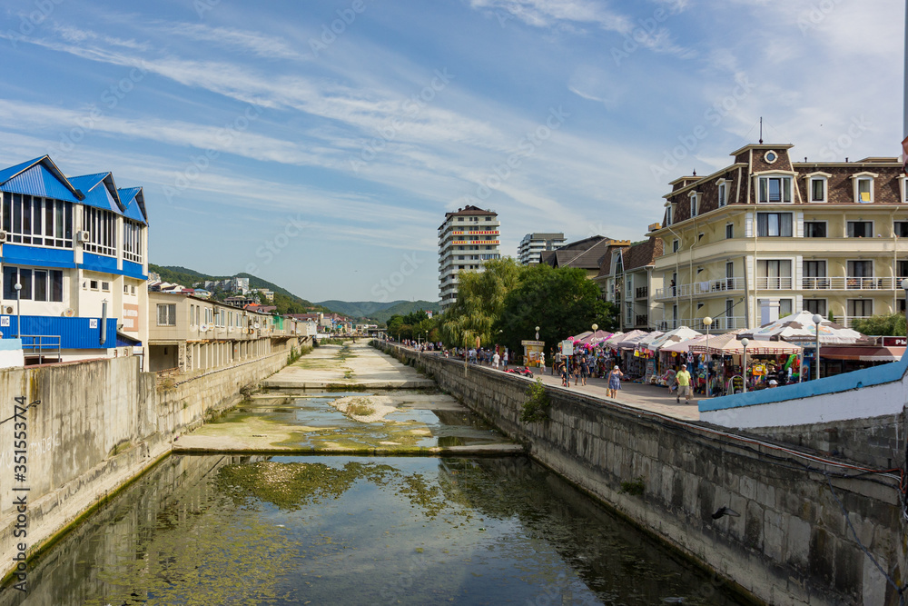 Naklejka premium Tuapse, Russia - September 14, 2019: Mountain river in concrete channel in village of Olginka, Tuapse district. River flows between village and sea. Tourist hotels were built on both concrete banks.