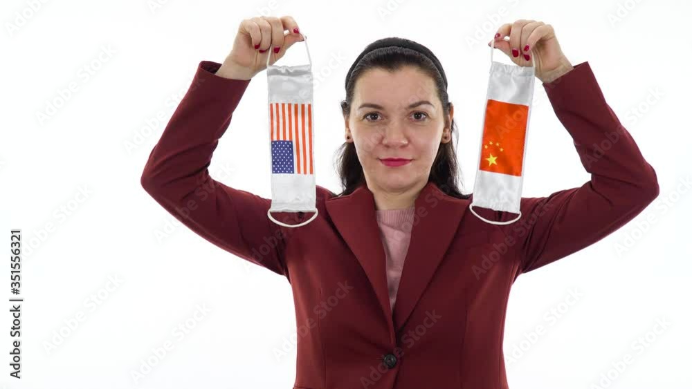 Virus and disease prevention concept. Pandemic and quarantine concept. Caucasian woman holds a protective medical mask with the image of the flag of China and the USA. Layout on white. Virus and disease prevention concept. Pandemic and quarantine concept. Caucasian woman holds a protective medical mask with the image of the flag of China and the USA. Layout on white.