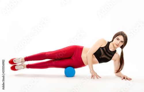 young, slender girl does sports exercises on the floor with a massage roller, isolated on white background