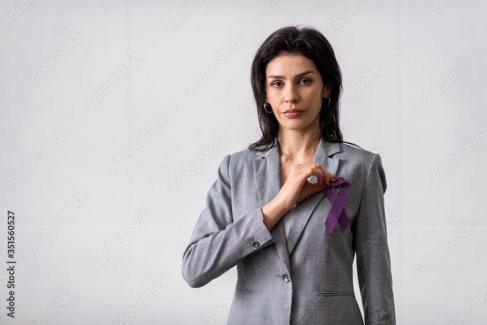 businesswoman holding purple ribbon and looking at camera on white, domestic violence concept businesswoman holding purple ribbon and looking at camera on white, domestic violence concept