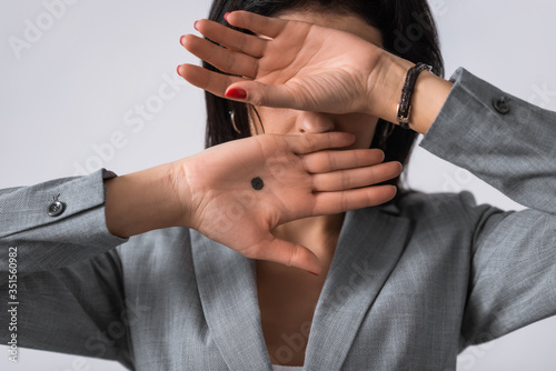 businesswoman with black dot on palm covering face isolated on white, domestic violence concept
